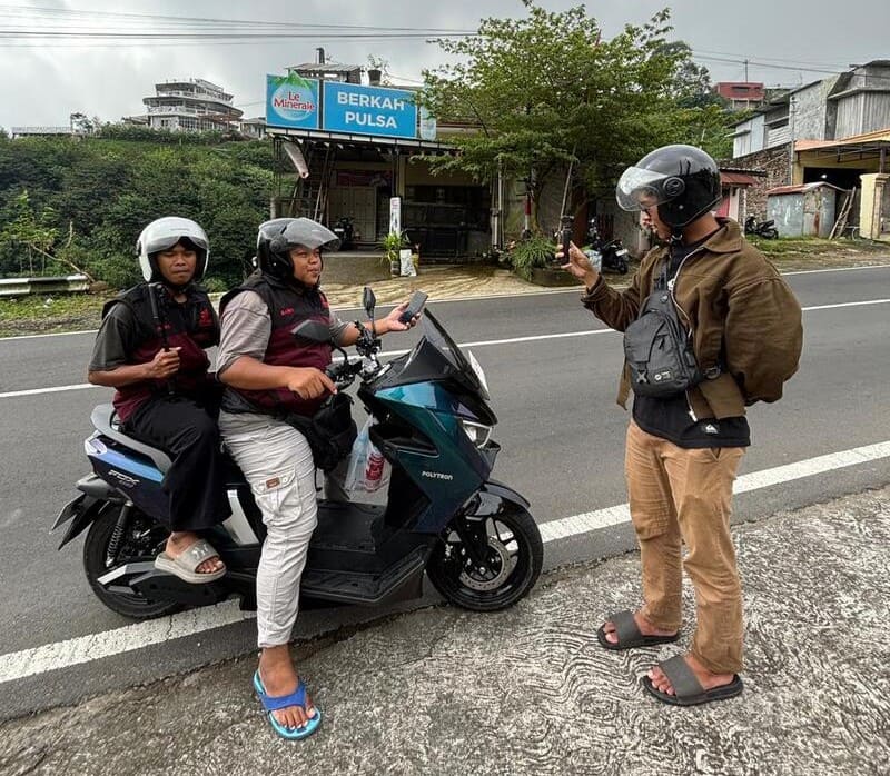 Petugas rental sedang menjelaskan fitur panel instrumen motor listrik kepada penyewa